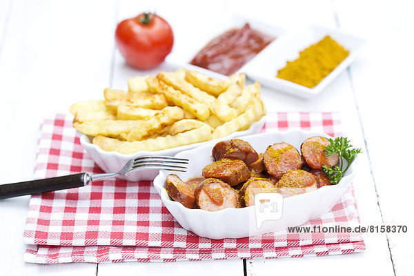 Bowl of sausages with french fries  currywurst and ketchup on wooden table  close up
