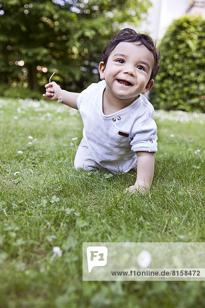 Kleiner Junge krabbelt auf Gras  lächelnd