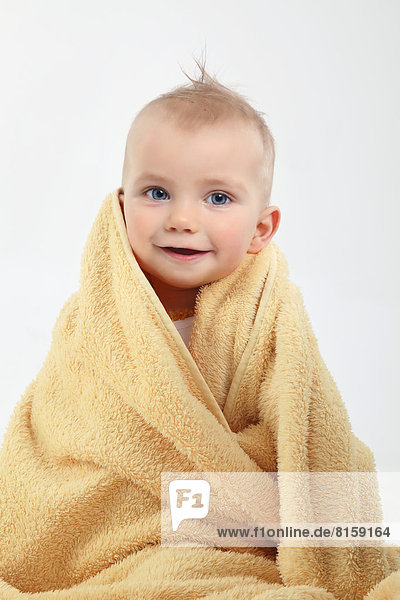 Portrait of baby boy wrapped in yellow towel  smiling