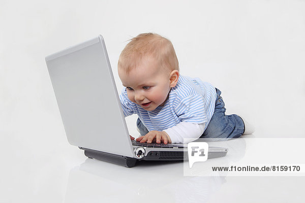 Baby boy using laptop on white background  smiling