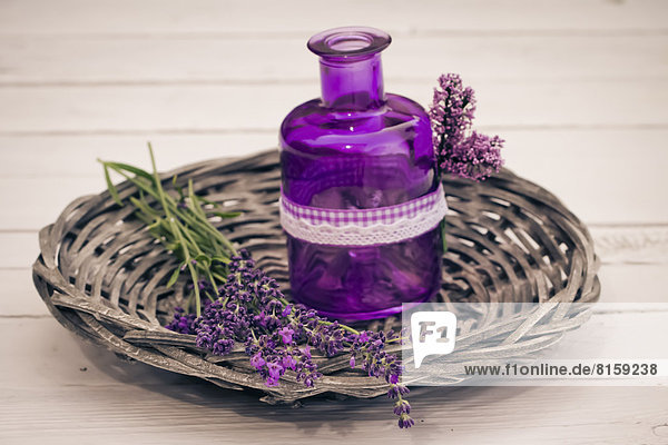 Lavendelblüten mit Korb und Flasche auf Holztisch  Nahaufnahme
