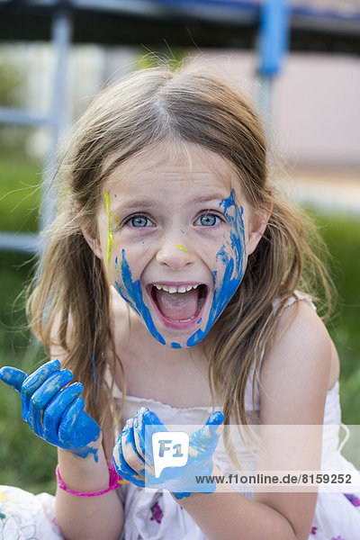 Portrait of girl playing with finger paint  smiling