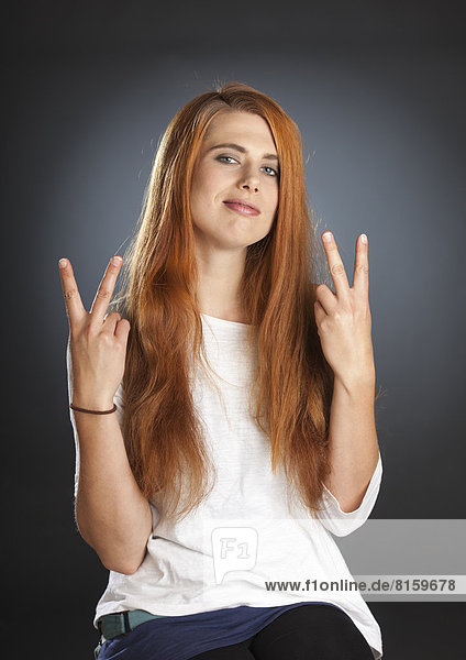 Portrait of young woman with victory sign
