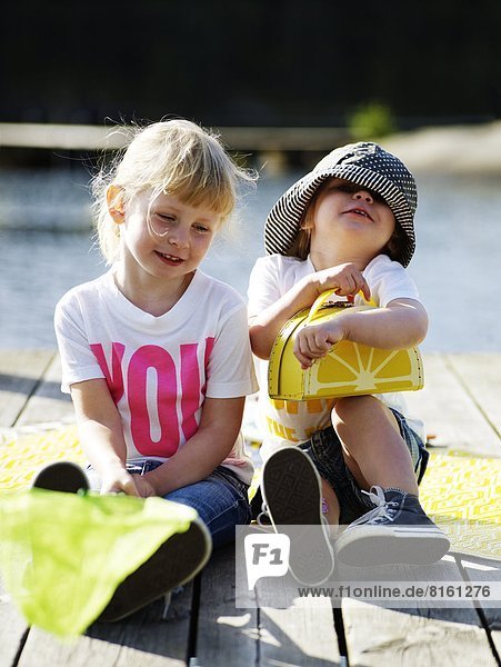 Smiling girls sitting on jetty