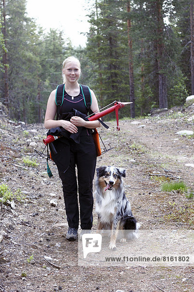 Smiling young woman with dog in forest
