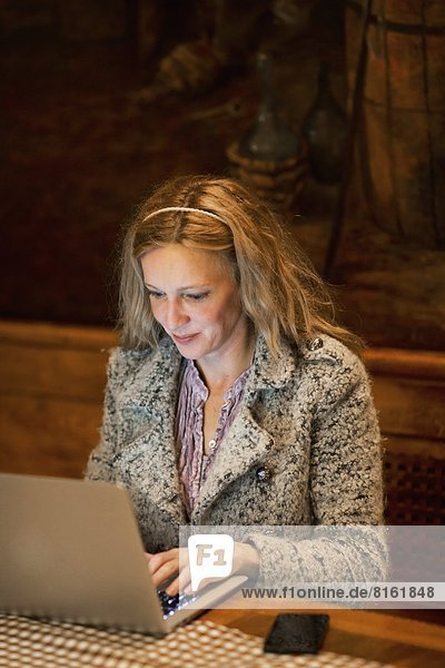 Mature woman using laptop in bar