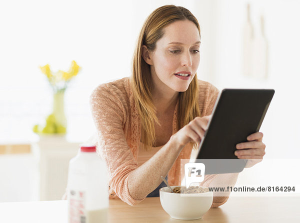 Frau  Computer  sehen  essen  essend  isst  Tablet PC  Frühstück