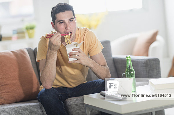 Man eating take out meal and watching television