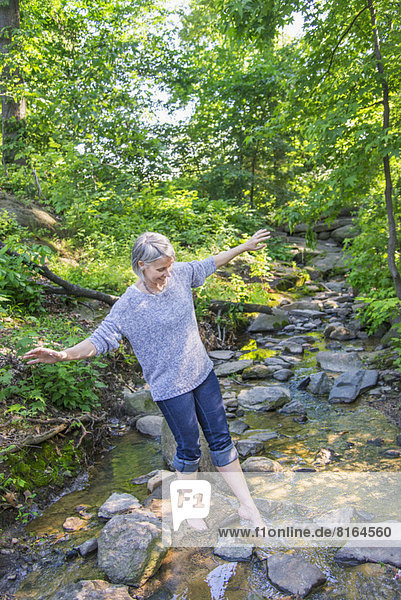 Senior woman crossing stream