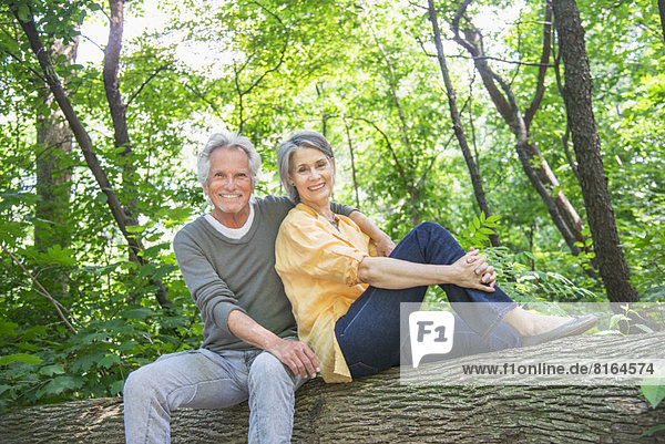 Senior couple sitting on log in forest