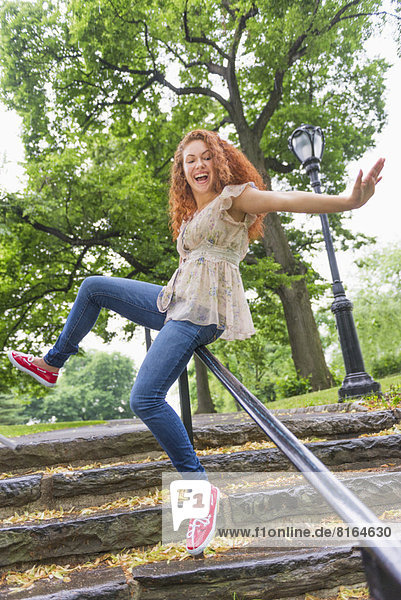 Woman sliding on railing in park