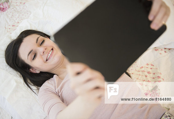 liegend  liegen  liegt  liegendes  liegender  liegende  daliegen  Portrait  Frau  halten  Bett  jung  Tablet PC
