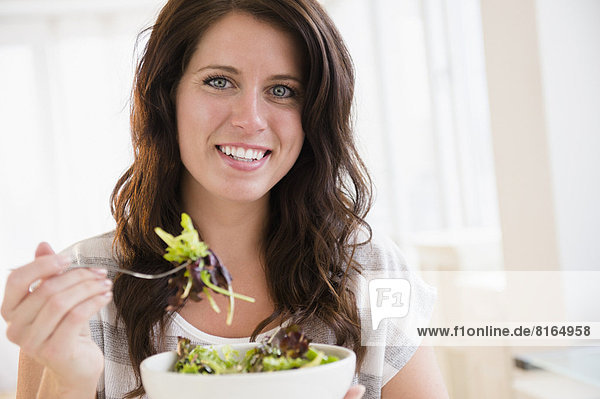 Portrait of young woman eating fresh salad
