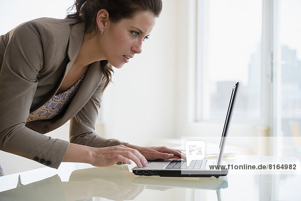 Busy woman in office using laptop