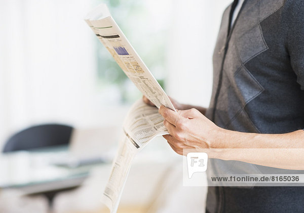 Mid section of man holding newspaper