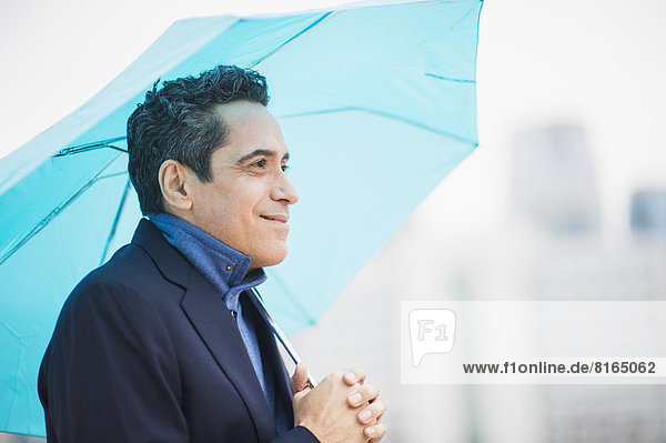 Portrait of man holding blue umbrella