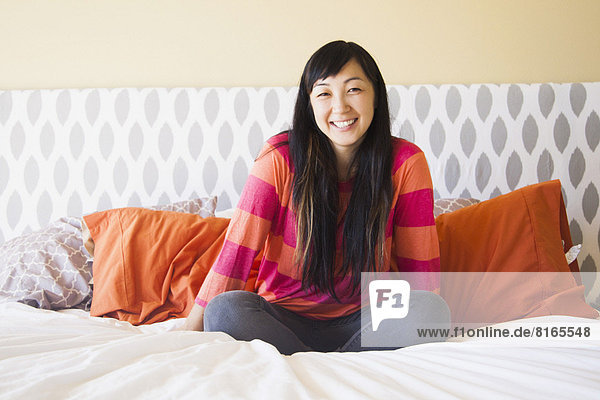 Portrait of mid adult woman sitting on bed