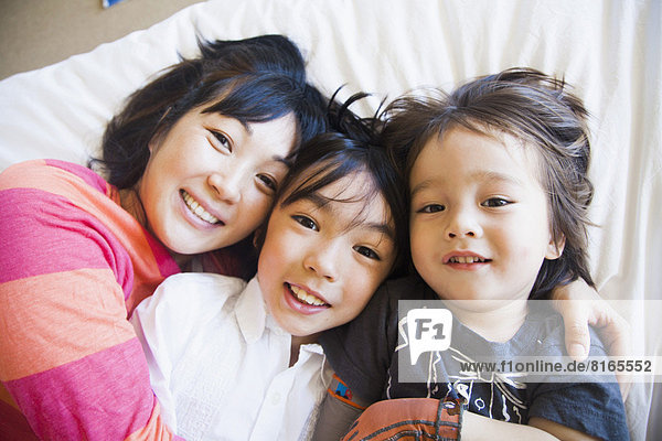 Mother with children cuddling on bed
