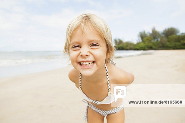 Smiling girl (2-3) on sandy beach