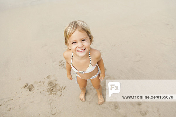 Smiling girl (2-3) on sandy beach