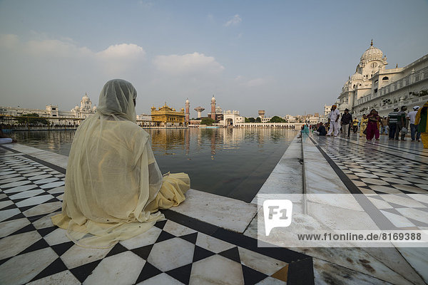 Eine gläubige Sikh sitzt am heiligen Teich  Harmandir Sahib oder Goldener Tempel  wichtigstes Heiligtum der Sikhs