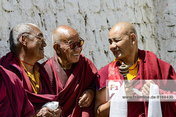 Three monks in the courtyard of Lamayuru Gompa