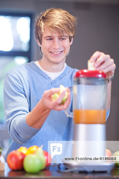 Junger Mann bereitet Fruchtgetränk zu
