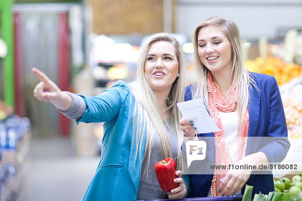 Zwei junge Frauen mit Einkaufsliste im Indoor-Markt