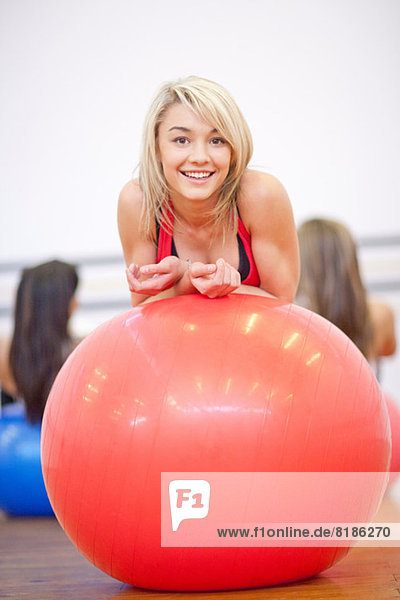 Young woman resting on exercise ball in aerobics class