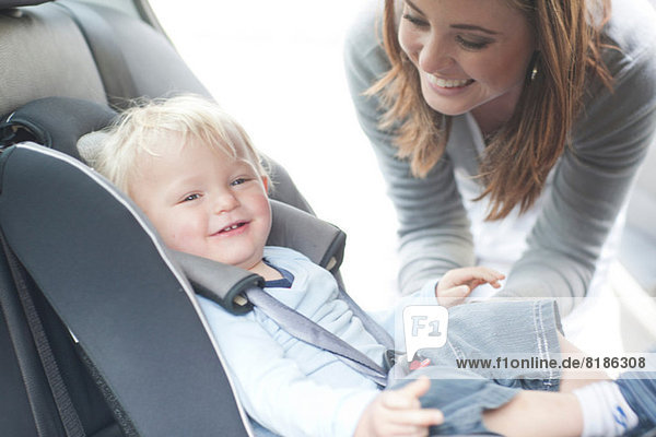 Mutter überprüft Baby-Sohn auf dem Rücksitz des Autos