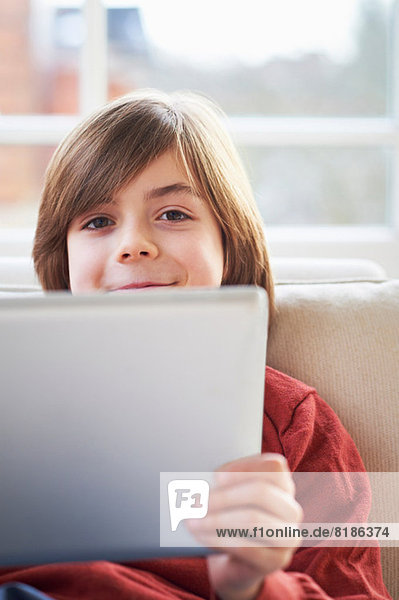 Junge auf Sofa mit digitalem Tablett