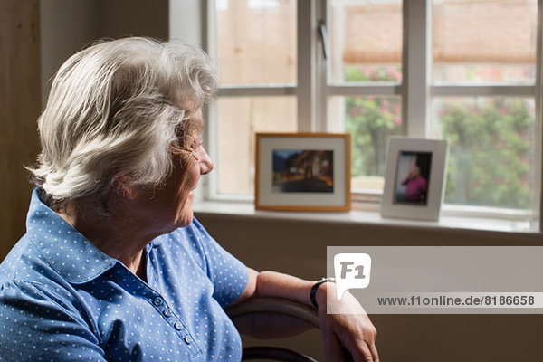 Senior adult woman sitting in room looking out of window