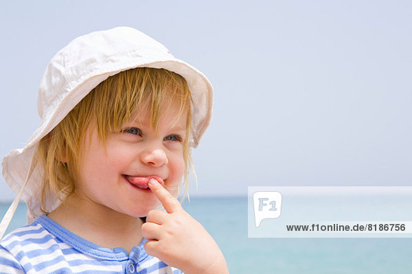 Portrait des Babys am Strand mit herausgezogener Zunge