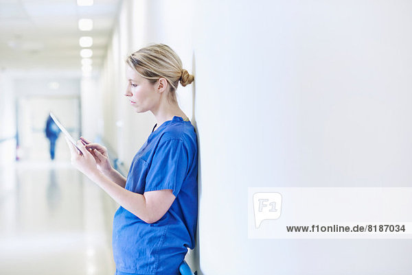 Doctor standing in corridor looking at digital tablet