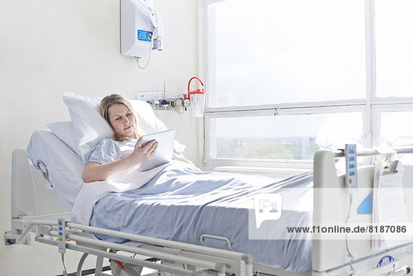 Patient lying on hospital bed using digital tablet