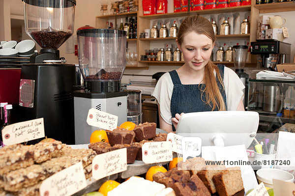 Young woman using cash register in cafe