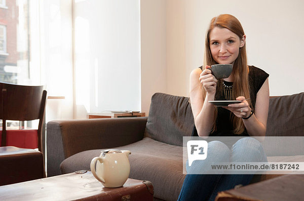 Porträt einer jungen Frau beim Tee trinken im Café