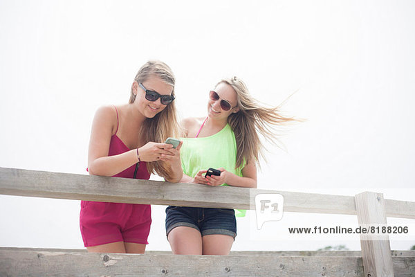 Junge Frauen benutzen Mobiltelefone am Pier