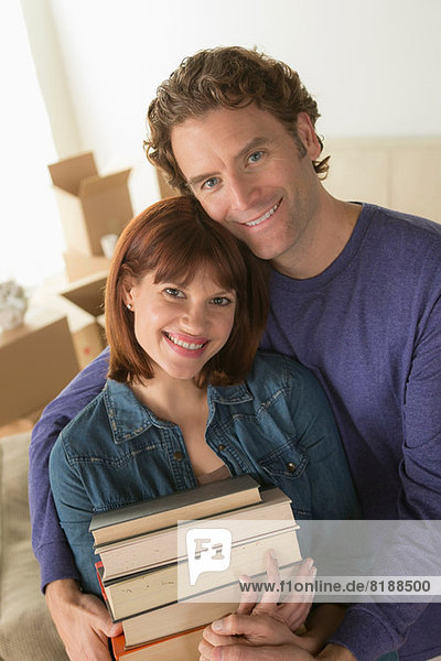 Couple holding pile of books