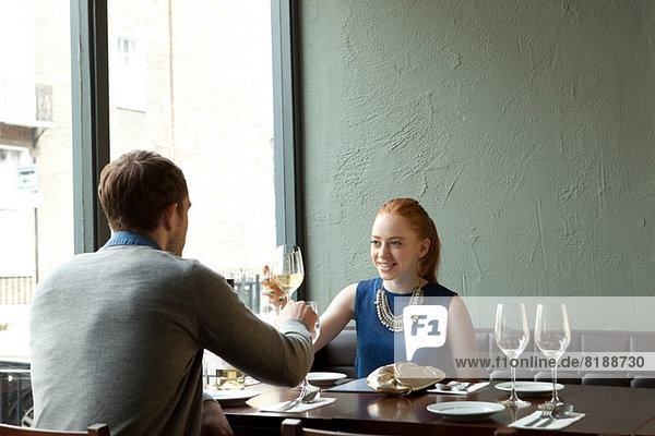 Young couple in restaurant toasting wine glasses