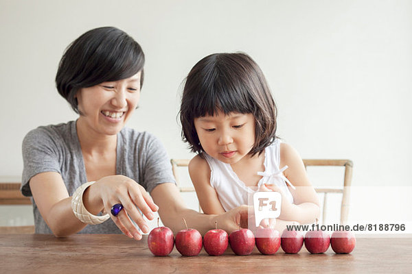 Mother and daughter with red apples in a row