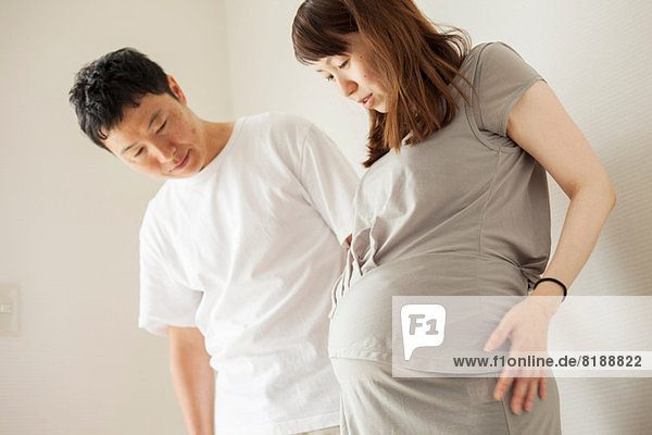 Man and pregnant woman looking down at stomach  portrait