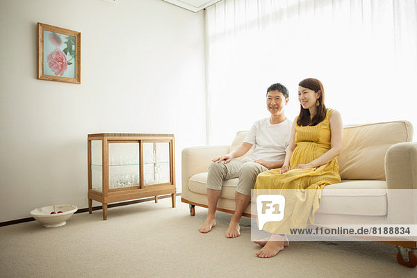 Man and pregnant woman sitting on sofa