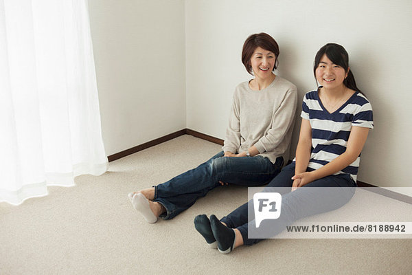 Mutter und jugendliche Tochter auf dem Boden sitzend  Porträt