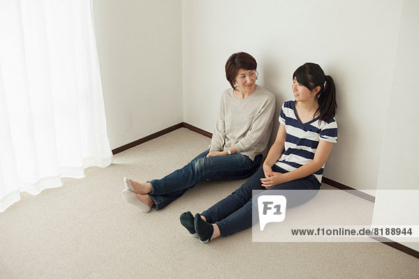 Mother and teenage daughter sitting on floor  portrait