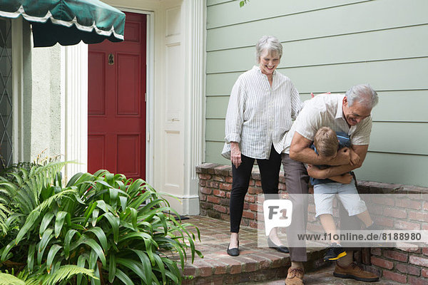 Älterer Mann spielt mit Enkel außerhalb des Hauses