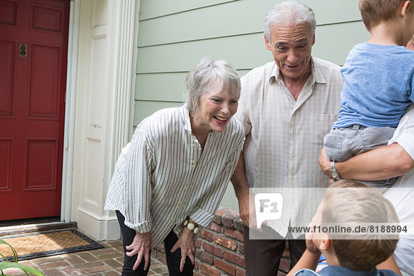 Senior couple greeting family at home