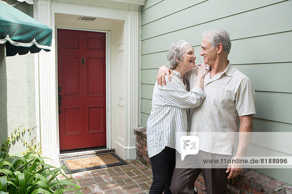 Seniorenpaar lächelt gemeinsam vor dem Haus