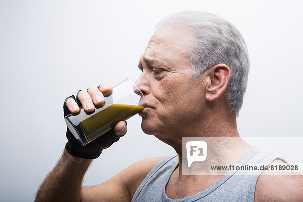 Senior Mann trinkt Smoothie aus Glas