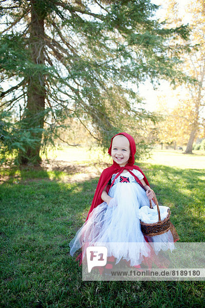 Weibliches Kleinkind im Wald in rotem Reiterhaube Kostüm